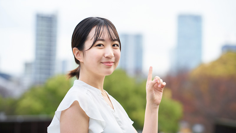 屋外で人差し指を立てる女性
