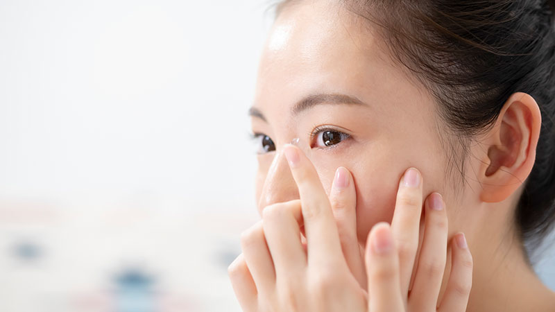 コンタクトレンズを目に装用しようとしている女性